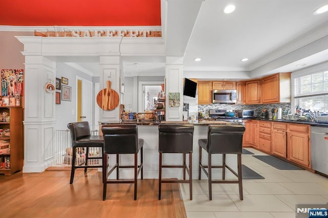 79 Newark Ave, Bloomfield, NJ 07003 - kitchen featuring appliances with stainless steel finishes, dark countertops, ornate columns, a breakfast bar, and ornamental molding