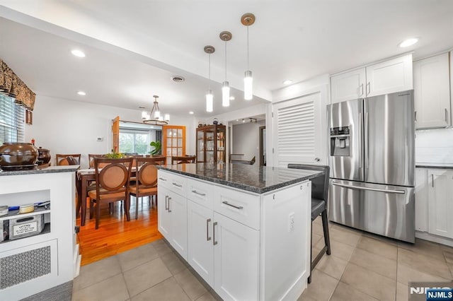 79 Newark Ave, Bloomfield, NJ 07003 - kitchen with stainless steel fridge with ice dispenser, light tile patterned floors, white cabinetry, a center island, and dark stone countertops