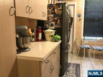 17 48th St, Weehawken, NJ 07086 - kitchen featuring light tile patterned floors, light countertops, and freestanding refrigerator