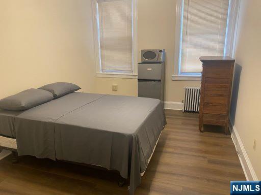 17 48th St, Weehawken, NJ 07086 - bedroom featuring radiator heating unit and wood finished floors