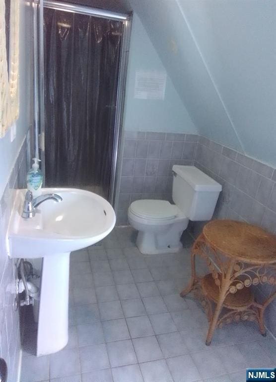 17 48th St, Weehawken, NJ 07086 - bathroom featuring tile walls, a shower stall, tile patterned floors, vaulted ceiling, and wainscoting