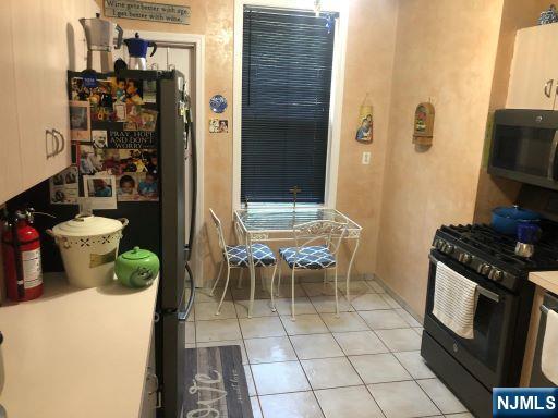 17 48th St, Weehawken, NJ 07086 - kitchen with black appliances and light tile patterned floors