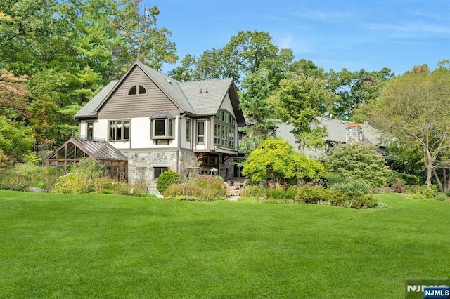 307 Freemans Ln, Franklin Lakes, NJ 07417 - rear view of house with stone siding, a yard, and a shingled roof