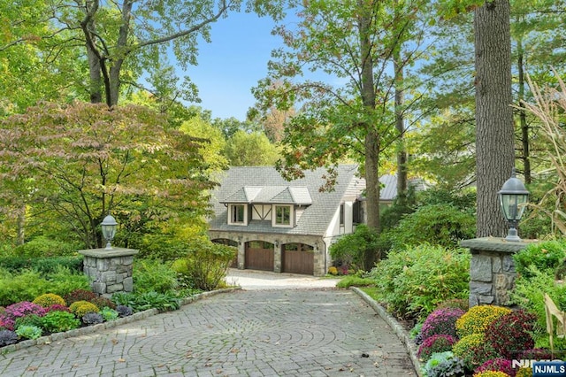 307 Freemans Ln, Franklin Lakes, NJ 07417 - tudor house with an attached garage, decorative driveway, and stone siding