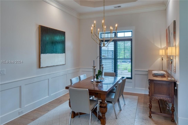 dining space featuring a notable chandelier, crown molding, and light hardwood / wood-style flooring