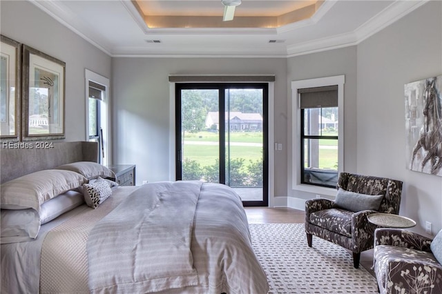 bedroom featuring ornamental molding, a raised ceiling, light wood-type flooring, and access to outside