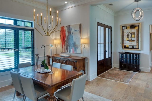 dining area featuring ornamental molding, french doors, a chandelier, and light wood-type flooring