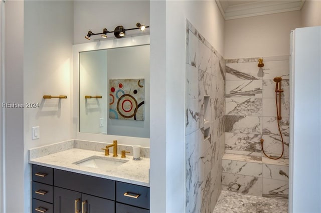 bathroom with a tile shower, vanity, and crown molding