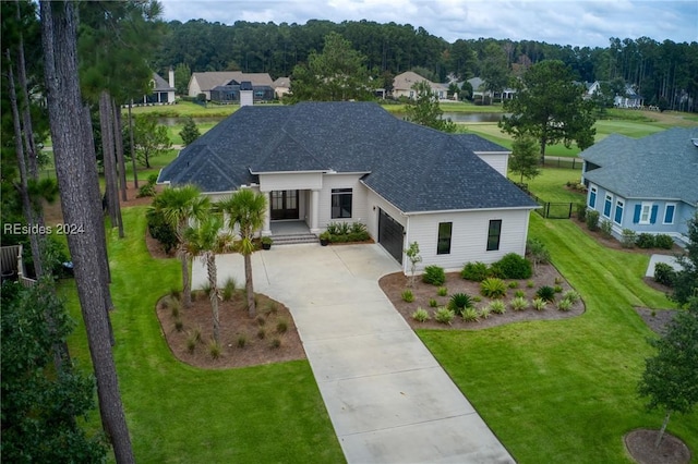 view of front of house with a garage, a front lawn, and a water view