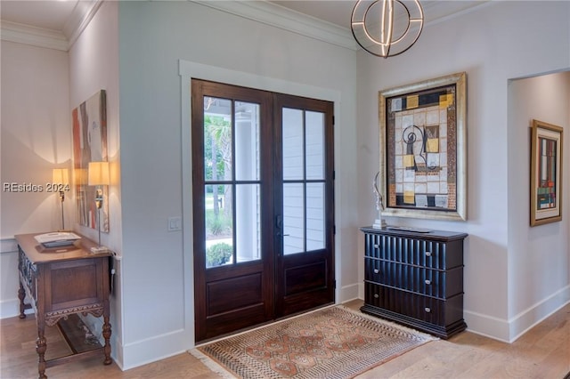 foyer entrance featuring ornamental molding, light wood-type flooring, and french doors