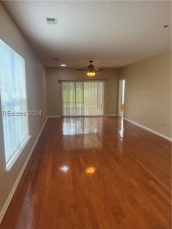 empty room with dark wood-type flooring, ceiling fan, and a textured ceiling