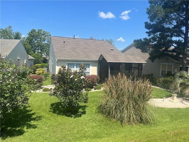 rear view of house featuring a lawn and a sunroom