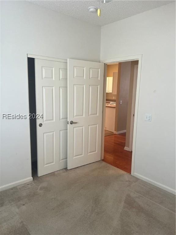 unfurnished bedroom featuring a closet, a textured ceiling, and carpet