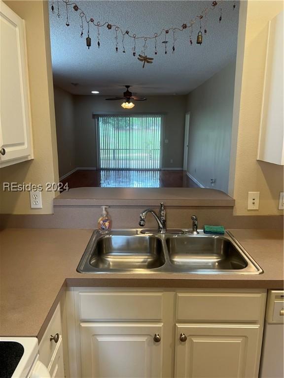 kitchen featuring sink, white appliances, white cabinets, and ceiling fan