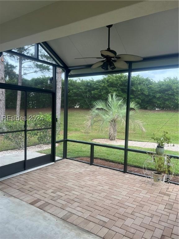 unfurnished sunroom featuring ceiling fan, a healthy amount of sunlight, and vaulted ceiling