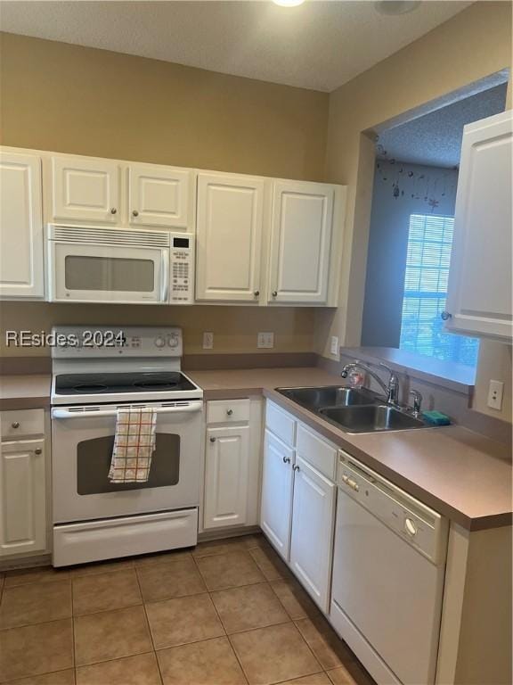 kitchen featuring white cabinetry, sink, white appliances, and light tile patterned floors