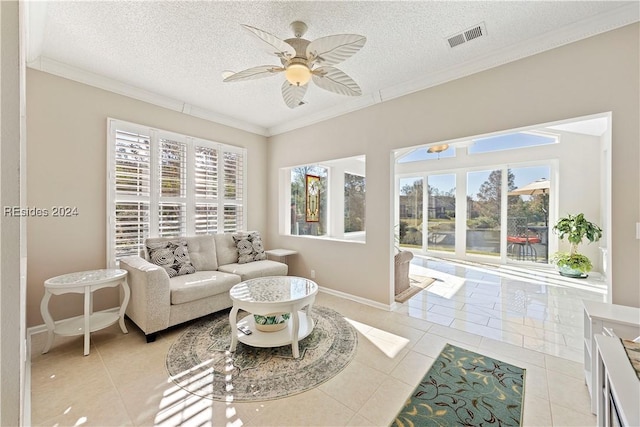 living room featuring light tile patterned flooring, ceiling fan, ornamental molding, and a textured ceiling