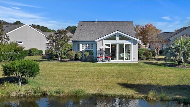 back of house featuring a water view and a lawn