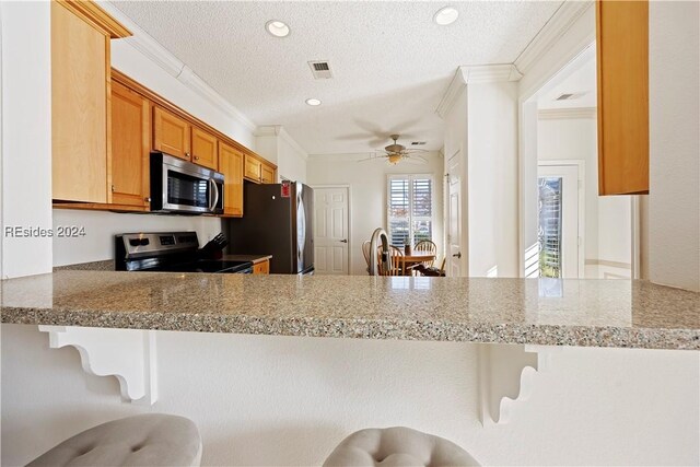 kitchen featuring stainless steel appliances, a textured ceiling, a kitchen bar, and kitchen peninsula