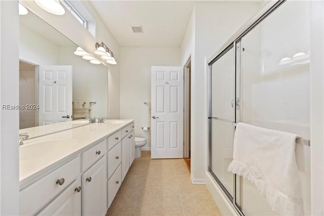 bathroom featuring tile patterned flooring, vanity, toilet, a shower with door, and a textured ceiling