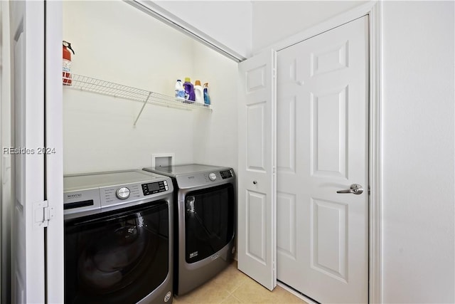 washroom with washing machine and dryer and light tile patterned flooring