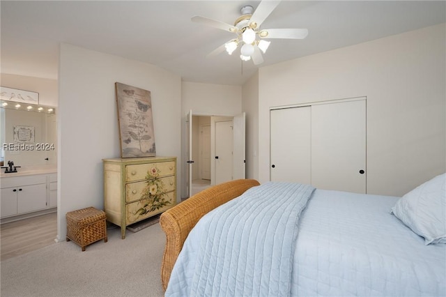 bedroom featuring connected bathroom, sink, ceiling fan, light carpet, and a closet