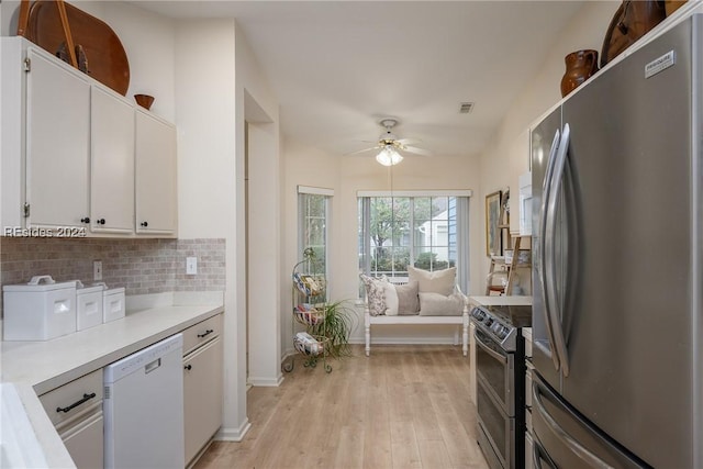 kitchen with light hardwood / wood-style flooring, appliances with stainless steel finishes, white cabinets, ceiling fan, and backsplash