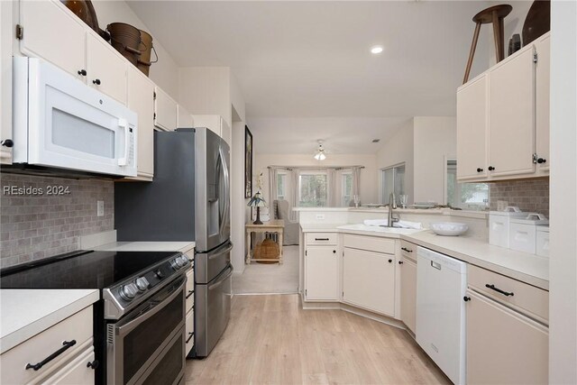 kitchen featuring sink, white cabinetry, tasteful backsplash, light wood-type flooring, and white appliances