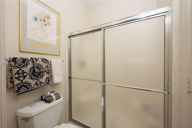 bathroom featuring toilet and a shower with shower door