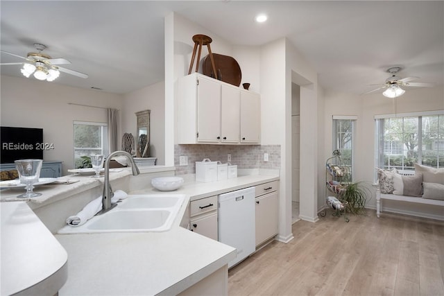 kitchen featuring sink, white cabinetry, tasteful backsplash, light wood-type flooring, and white dishwasher