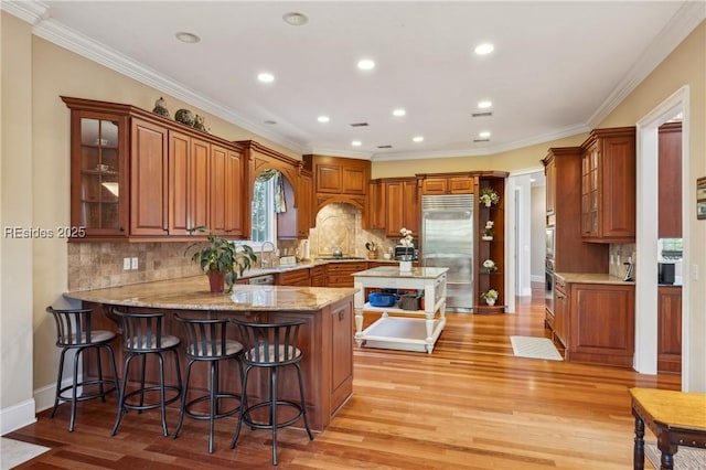 kitchen with light hardwood / wood-style flooring, ornamental molding, kitchen peninsula, and stainless steel built in fridge