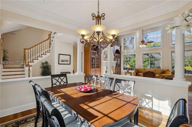 dining space featuring decorative columns, crown molding, wood-type flooring, and ceiling fan with notable chandelier