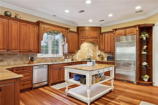 kitchen with sink, crown molding, light hardwood / wood-style flooring, stainless steel appliances, and light stone counters