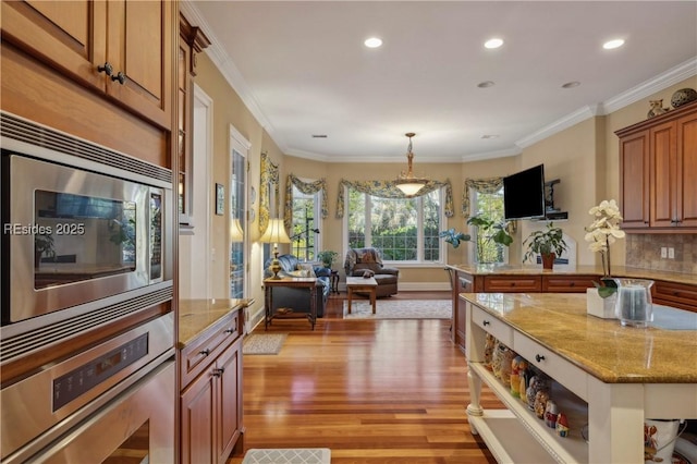 kitchen with ornamental molding, appliances with stainless steel finishes, light stone countertops, and light hardwood / wood-style flooring