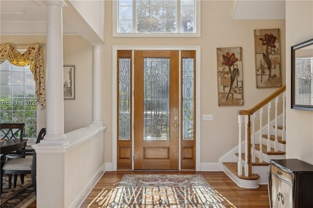 entrance foyer featuring decorative columns, ornamental molding, hardwood / wood-style floors, and a wealth of natural light