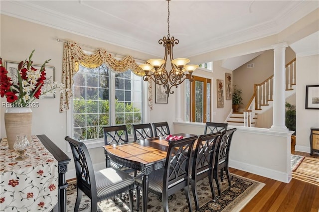 dining room with ornamental molding, dark hardwood / wood-style flooring, a chandelier, and decorative columns