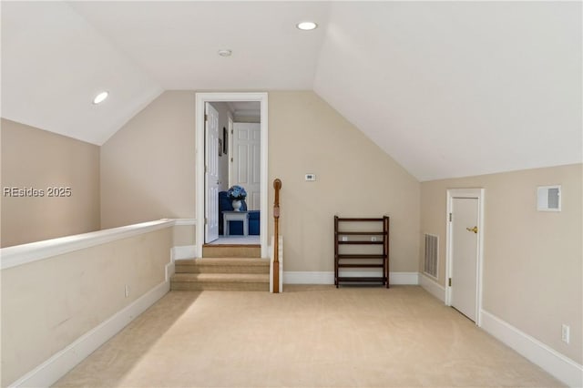 additional living space featuring light colored carpet and lofted ceiling