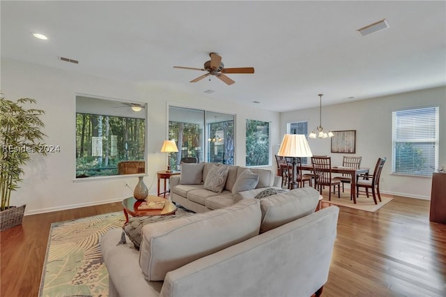 living room with hardwood / wood-style floors and ceiling fan with notable chandelier