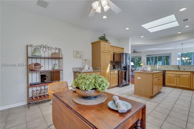 tiled dining area featuring ceiling fan and a skylight