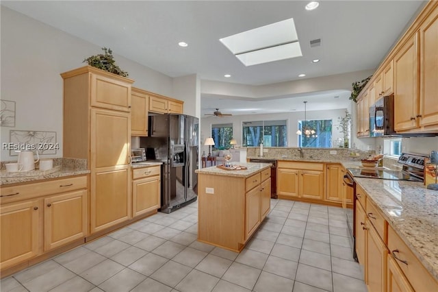 kitchen featuring a skylight, a center island, hanging light fixtures, kitchen peninsula, and black appliances