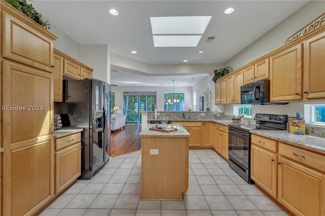 kitchen with light tile patterned flooring, black appliances, kitchen peninsula, and a kitchen island