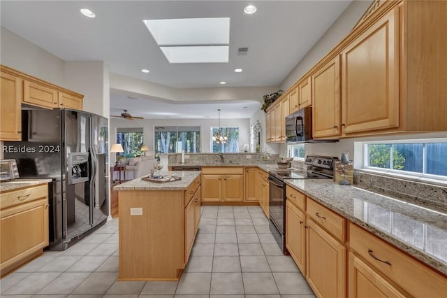 kitchen featuring pendant lighting, a kitchen island, black appliances, light tile patterned flooring, and kitchen peninsula