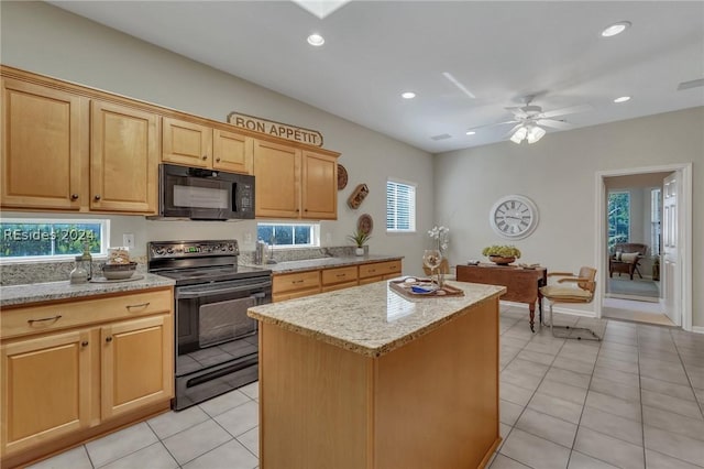 kitchen with a healthy amount of sunlight, light tile patterned floors, a kitchen island, and black appliances