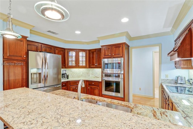 kitchen featuring pendant lighting, crown molding, appliances with stainless steel finishes, backsplash, and light stone counters