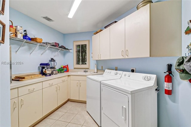 laundry area featuring sink, light tile patterned floors, cabinets, and washing machine and clothes dryer