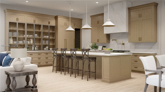 kitchen featuring pendant lighting, sink, backsplash, a center island with sink, and light wood-type flooring