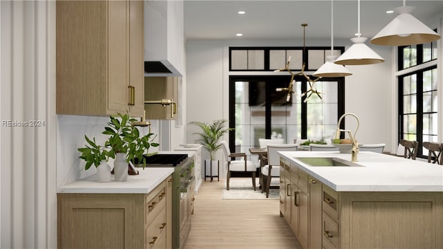 kitchen with pendant lighting, sink, high end range, a healthy amount of sunlight, and a center island with sink