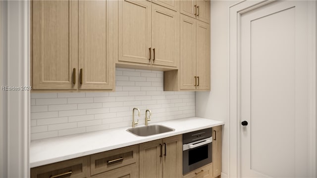 kitchen featuring light brown cabinetry, backsplash, sink, and stainless steel oven