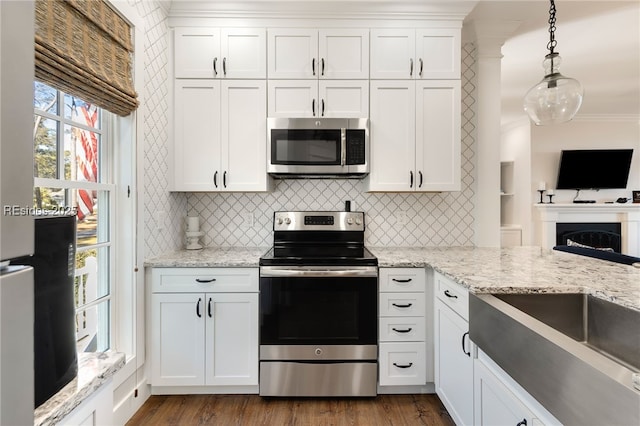 kitchen with pendant lighting, white cabinetry, appliances with stainless steel finishes, and light stone counters