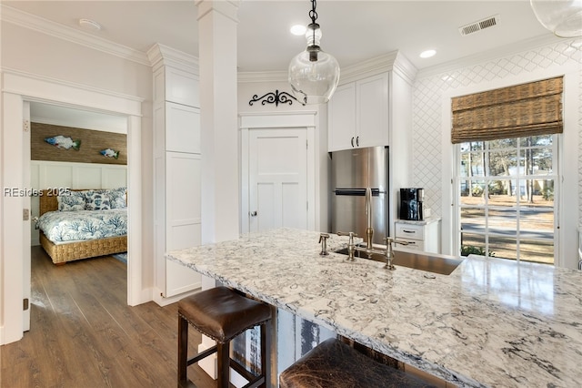 kitchen featuring crown molding, stainless steel fridge, dark wood-type flooring, white cabinetry, and decorative light fixtures